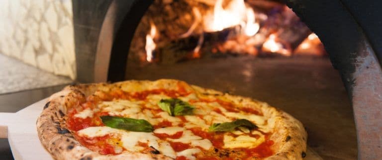 content-pizza-being-baked-inside-a-custom-pizza-oven-for-outdoor-kitchen-768x323